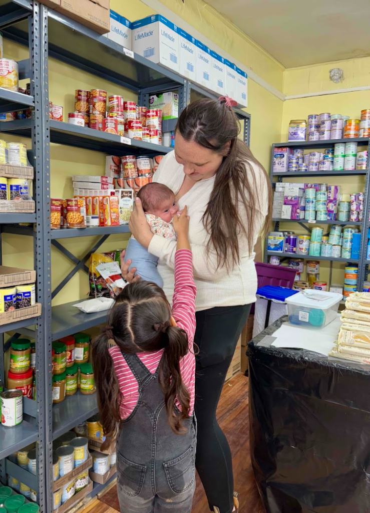 Woman holding her infant with toddler in foreground